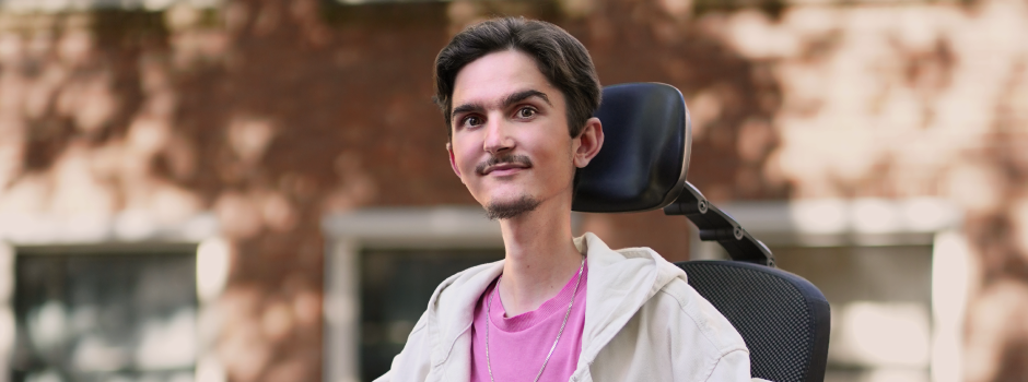 Endri, op TikTok bekend als Lilhandi, in zijn elektrische rolstoel, lachend naar de camera
