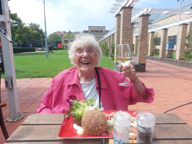 Geertje houdt een glas witte wijn omhoog tijdens de lunch op het terras