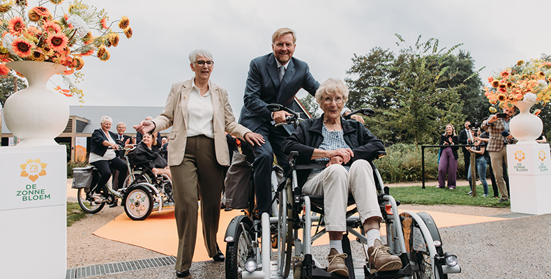 Koning Willem-Alexander fietst met een deelnemer op de Zonnebloemfiets