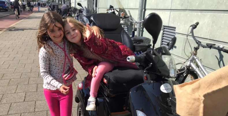 Sanne's dochter Rosie met haar vriendinnetje op de nieuwste scootmobiel